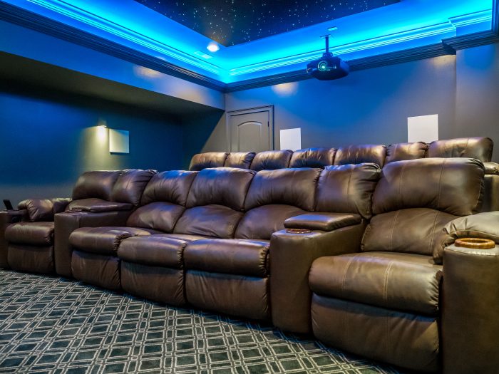 Home theater with blue LED cove lighting along the ceiling and leather recliners