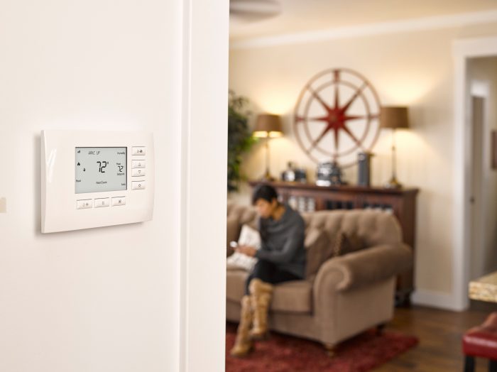 Homeowner adjusting a wall-mounted smart thermostat in a living room