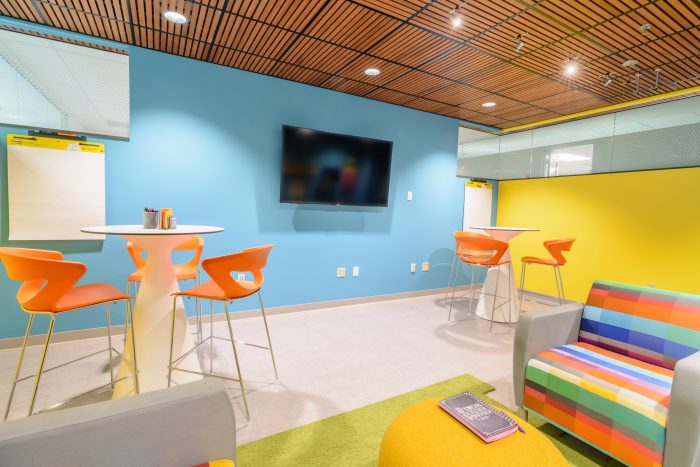 Conference room with a wall-mounted display, wood accent wall, and a tabletop touchscreen controller